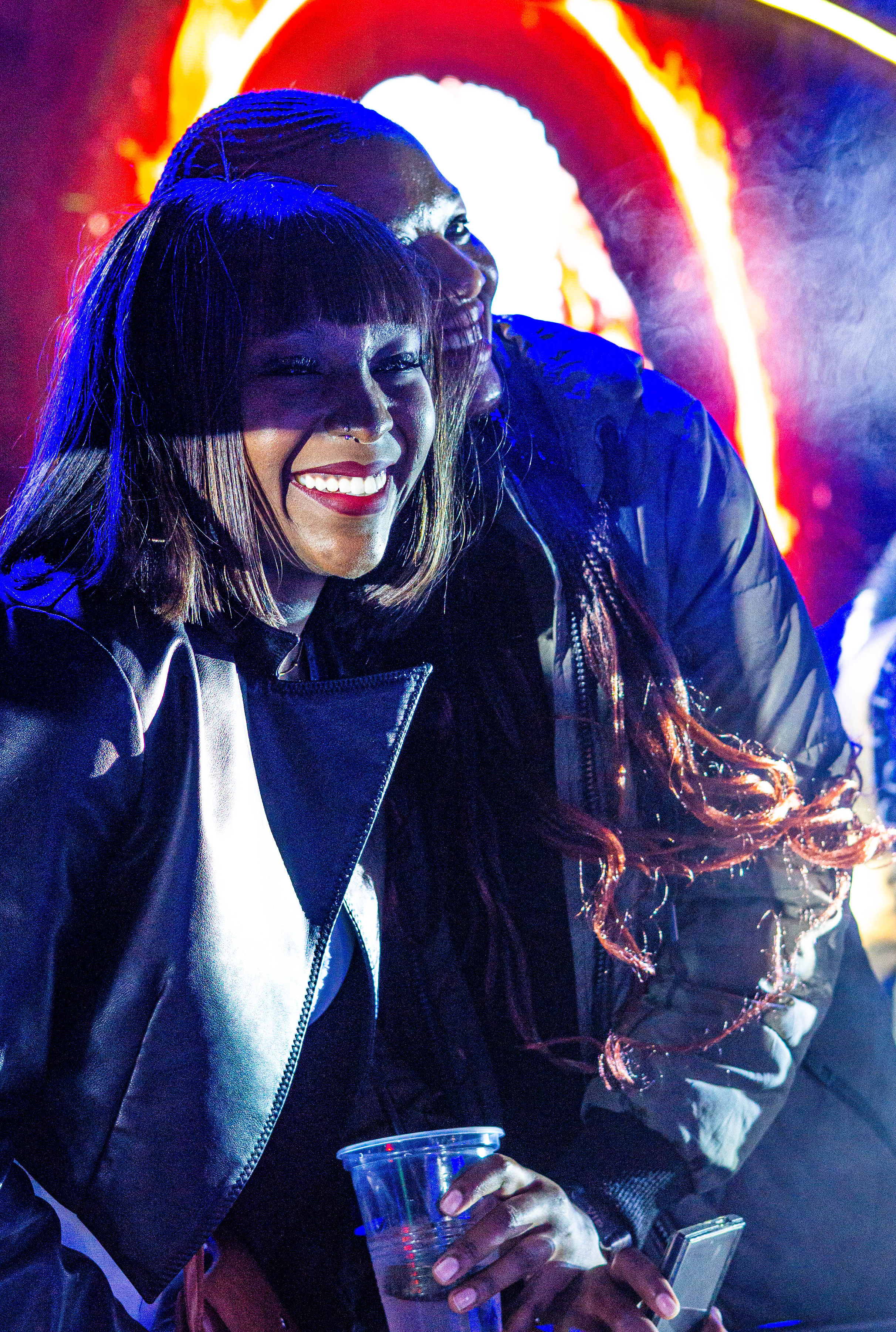 Friends smiling together under blue festival lights