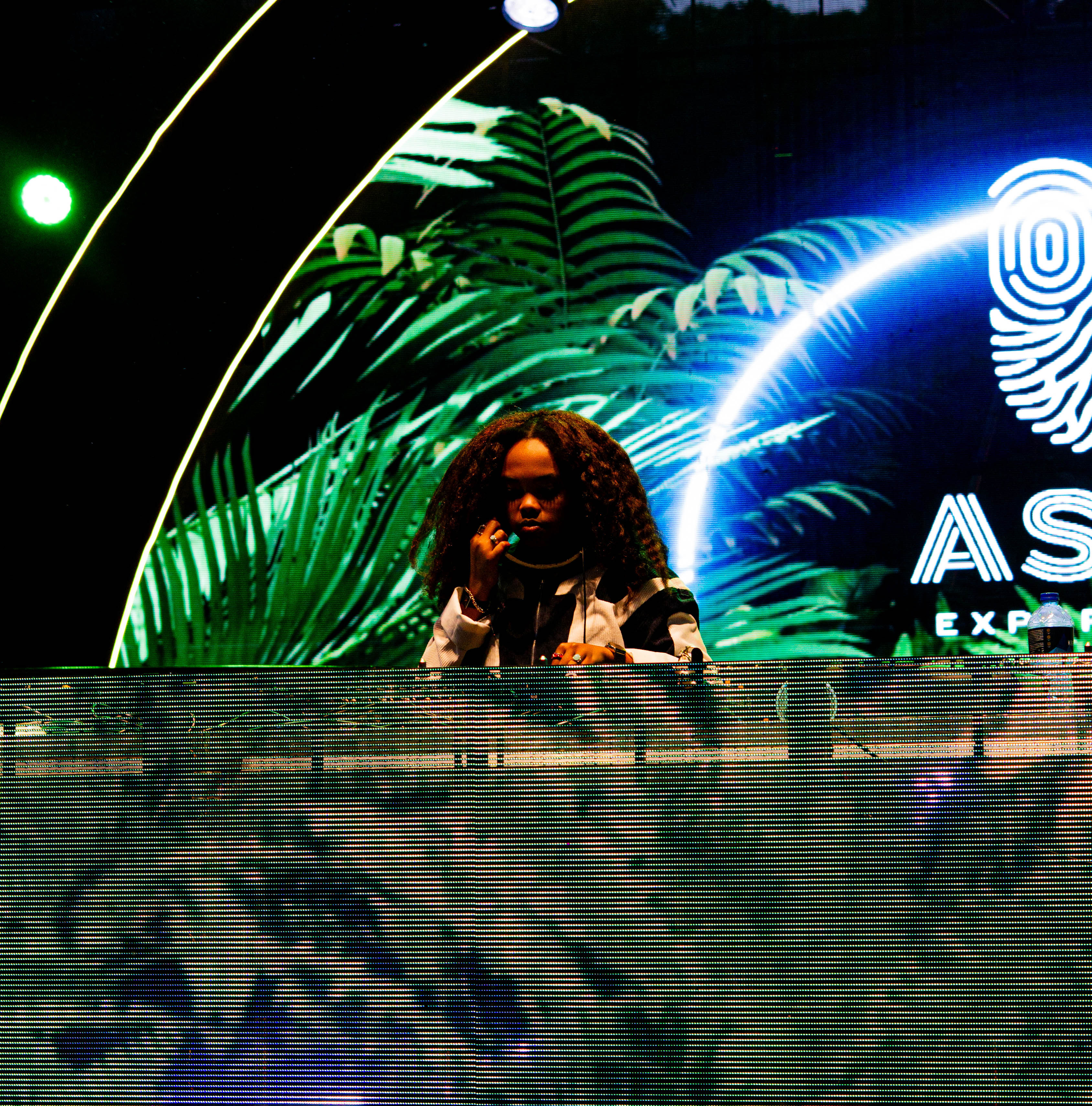 DJ performing against green ASILI stage visuals